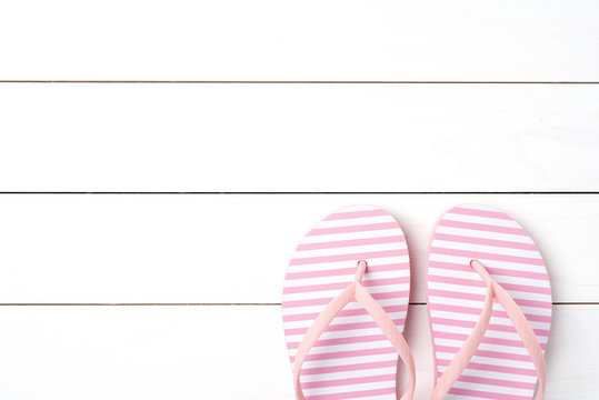 Pink flip flops on white wooden background
