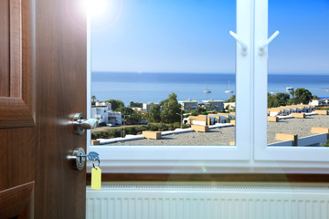 Widok z okna hotelu na dachy domów i morze. - obrazy, fototapety, plakaty
