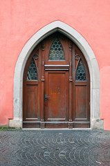 Old arched wooden door on pink wall. Ravensburg, Baden-Wurttemberg, Germany.