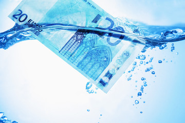 Money concept showing Euro banknote sinking in water as a symbol of global economic crisis