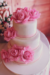 Wedding cake covered with white icing and decorated with pink roses