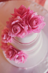 Wedding cake covered with white icing and decorated with pink roses