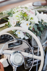 Wedding bouquet lies behind the steering wheel in the car