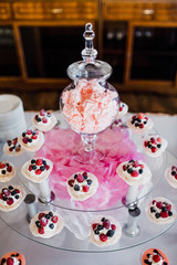 Cupcakes with white cream and forest berries served on glass dish