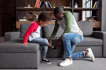 father putting shoes on son