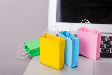 Color packs for purchases and a laptop on a gray background. Copy space for text