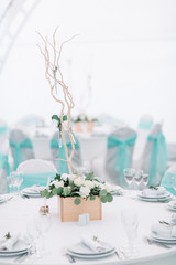 Wooden box with white roses stands in the middle of a dinner table