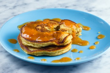 Two crumpets from gluten free flour with peach preserve on blue plate