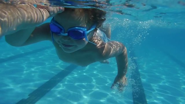 Little boy / kid diving underwater swiminng pool summer