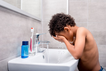 little afro kid washing face