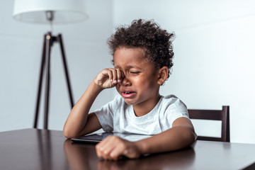 boy crying while sitting with tablet