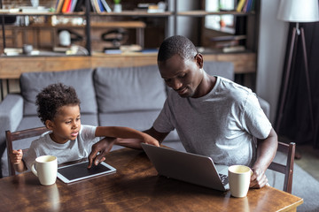 father and son using laptop and tablet