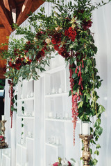 Fototapeta na wymiar Wedding altar made of white shelves and dark red flowers