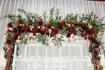 Wedding altar made of white shelves and dark red flowers