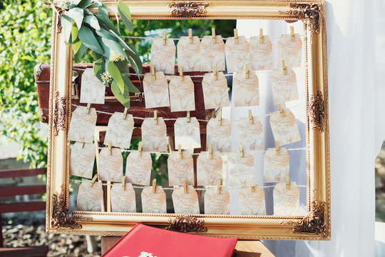 Empty wooden frame with greenery and cards with guests' names