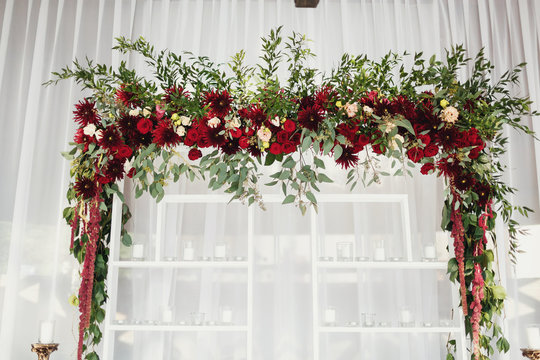 Wedding Altar Made Of White Shelves And Dark Red Flowers