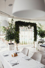 Wedding altar made of greenery stands before a panoramic window