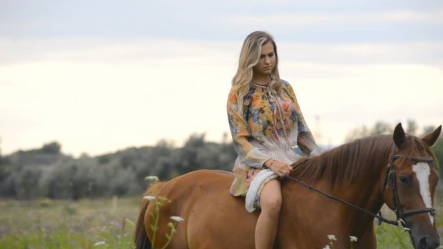 Young woman riding a horse in summer