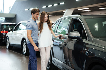 Beautiful young couple standing at the car dealership