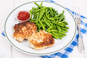 Lunch from green beans and cutlets on white wooden table