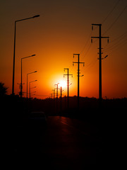 Fototapeta na wymiar road with power line and lamp posts in sunset