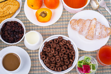 Fototapeta na wymiar Breakfast table with croissant, muesli, milk, honey and fruits
