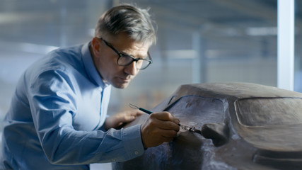 Professional Automotive Designer with Rake Sculpts Futuristic  Car Model from Plasticine Clay. He...