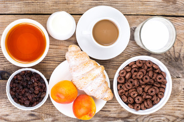 Obraz na płótnie Canvas Chocolate cereal flakes, coffee, milk, croissant and fruit for b
