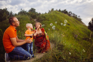 Mom and dad blow soap balloons with their son