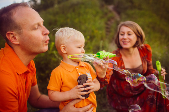 Mom And Dad Blow Soap Balloons With Their Son