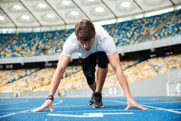 Confident male athlete standing in starting position ready for running