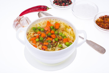 Noodle soup with green peas and carrots on white background