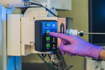 Scientist in a laboratory works with an electron microscope gateway. Putting a sample into a microscope chamber