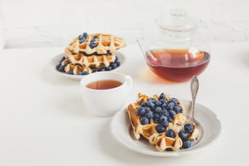 delicious breakfast of belgian waffles with blueberries and tea