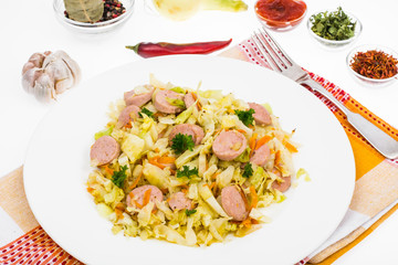 White plate with braised cabbage and sausages