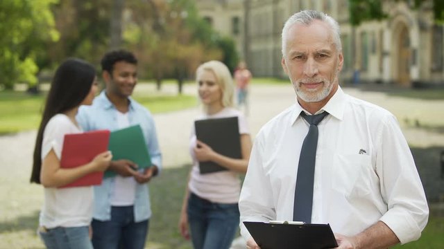 Professor and students standing near university, dean looking into camera