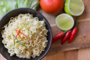 Instant noodles in black bowl on wood background, Asian meal on a table