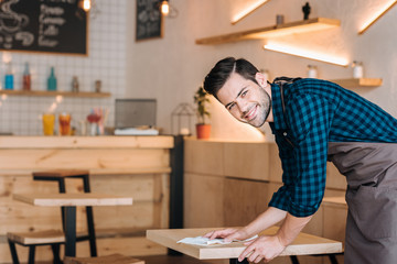 worker cleaning table in cafe