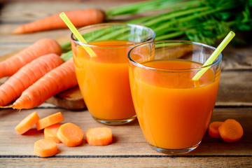 Jus de carotte frais dans des verres sur une table en bois rustique.
