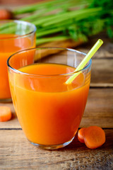 Fresh carrot juice in glasses on rustic wooden table.