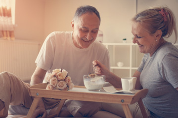 Senior couple having healthy breakfast together in bed.