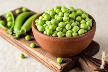 Fresh green peas in ceramic bowl on gray stone background