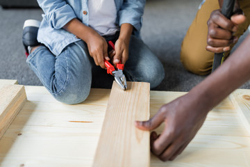 cropped shot of father and son pulling screw out of plank