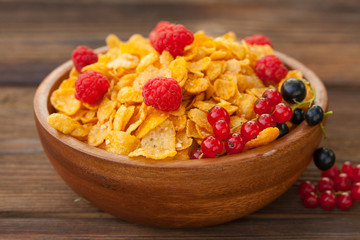 Breakfast of cornflakes with berries in wooden bowl