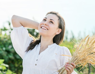 Portrait of a Beautiful laughing sexy female with long hair holding wheat ears outdoors ay summer day