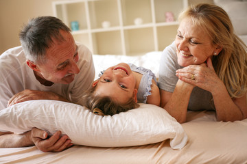 Grandmother and grandfather lie together with their granddaughter.