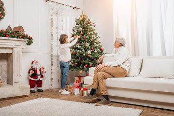 grandfather and granddaughter decorating christmas tree