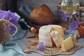 A head of fresh organic cheese served with bread, nuts, white wine and summer flowers.