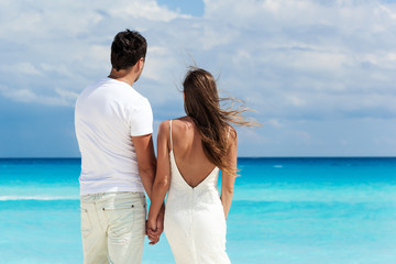 Newlyweds in love on beach looking to the sea