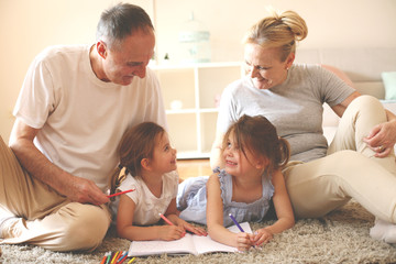 Grandmother and grandfathers teaching their granddaughter to write.